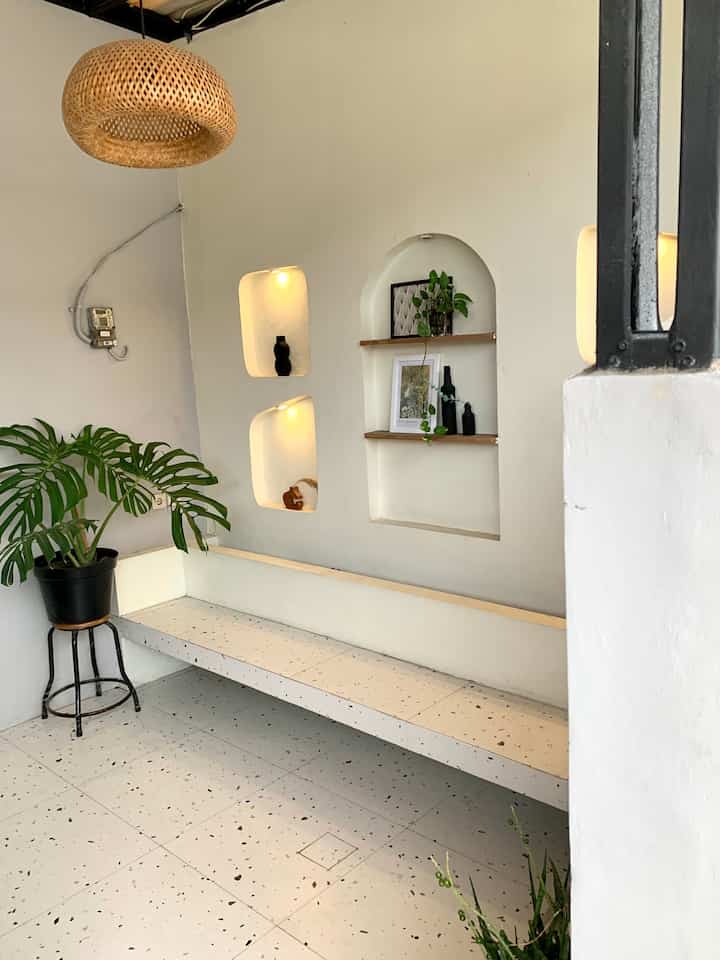 Natural-toned waiting area featuring white walls and a rattan pendant light with a simple, cozy atmosphere