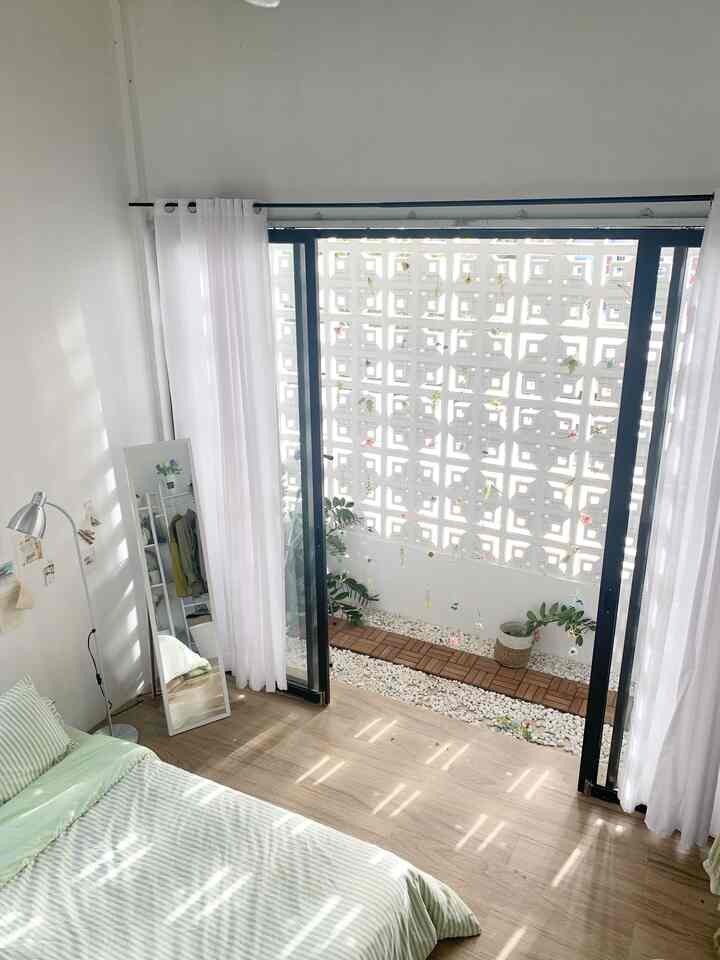 Natural bedroom with white and wood tones featuring a balcony with roaster facade and decking floor