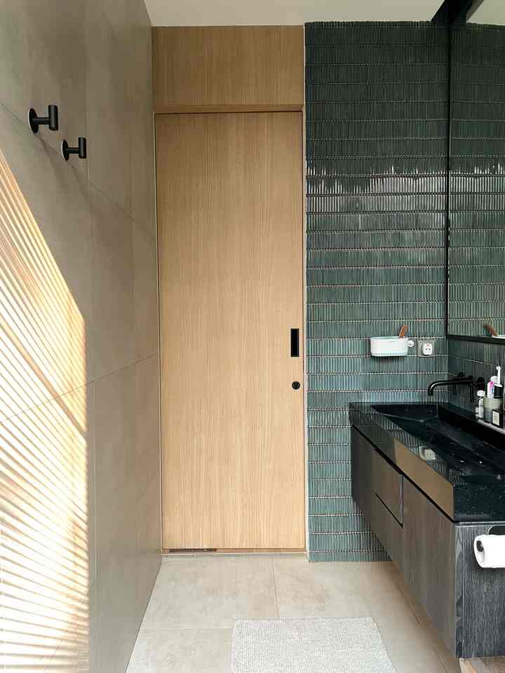 Kamar mandi ini berada di dalam master bedroom. Untuk kamar mandi ini kami menggunakan dinding bahan granite dan sebagian nya lagi menggunakan keramik berwarna hijau tua untuk menambah kesan tropical.

Untuk kabinet wastafel kami menggunakan material kayu yang dilapis HPL warna hitam dengan tekstur kayu, untuk wastafel nya sendiri aku custom dengan material solid surface supaya mendapatkan ukuran wastafel panjang yang diinginkan. Untuk hardware kamar mandi kami menggunakan warna hitam agar senada dengan warna wastafel dan kabinet. 
_
#MaterialKamarMandi
#KamarMandi
#InspirasiKamarMandi
#dirumahpojok
#BathroomMaterial