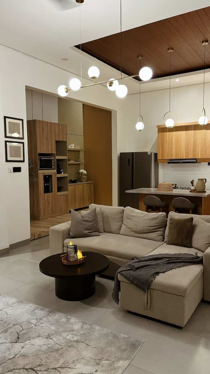 Modern and cozy living room and kitchen in beige and light brown tones featuring pendant lighting