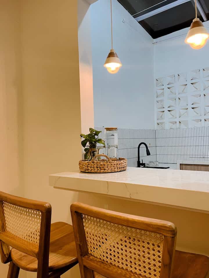 Hai , jadi ini salah satu tempat favorit ngobrol berdua bareng suami🤩

Ruangan ini terlihat cukup tenang dan minimalis. Pada malam hari, suasana ruangan akan diterangi oleh lampu gantung dengan cahaya kuning hangat, yang menciptakan kesan nyaman dan hangat. Pencahayaan lembut ini membantu memberikan suasana yang lebih intim dan santai. 

Bagian meja dihiasi dengan keranjang rotan yang berisi tanaman kecil, dan beberapa gelas kaca yang tertata rapi, menambah sentuhan alami dan estetika sederhana. Kursi kayu dengan anyaman rotan melengkapi kesan alami dan membuat ruangan terasa lebih homy. 

Di belakang, area dapur dengan backsplash berwarna putih dan keran hitam modern memberikan kontras yang bersih dan elegan. Pencahayaan dari lampu utama akan memantulkan kilauan lembut di meja Granit, mempertegas nuansa ruangan yang tenang di malam hari.

#LampuRumah
#InspirasiLampu
#NightVibe
#LampuWarm
#LampuDapur
#LampuGantung
#LampuGantungKayu

