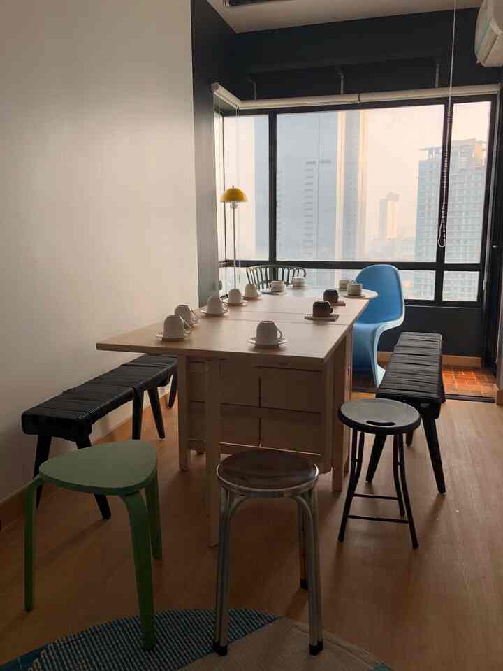 Cafe style dining room featuring wood tone floors and table, assorted color stools, with a prominent window city view