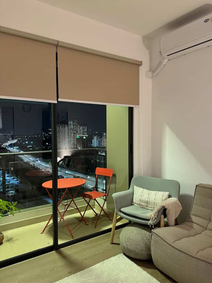 A beige-toned living room with balcony featuring a red table and chair, creating a natural and cozy atmosphere