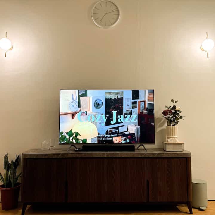 Beige-toned living room featuring a 55-inch TV centered on a wooden TV stand, creating a cozy atmosphere