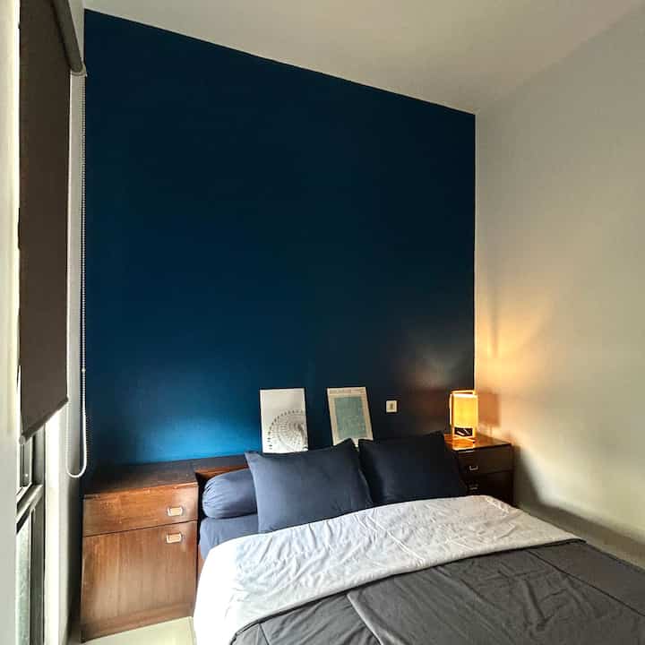 Small 3x3.5m bedroom with navy accent wall and wooden furniture, simple and cozy atmosphere