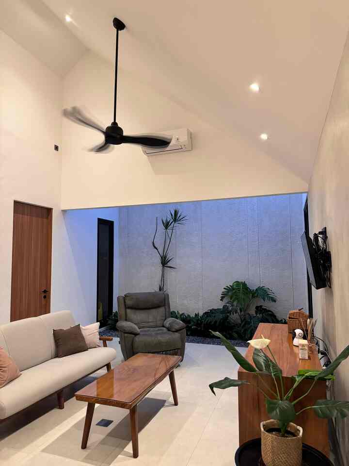 Natural modern living room with wood-tone table and gray recliner, featuring an indoor garden background creating a harmonious atmosphere