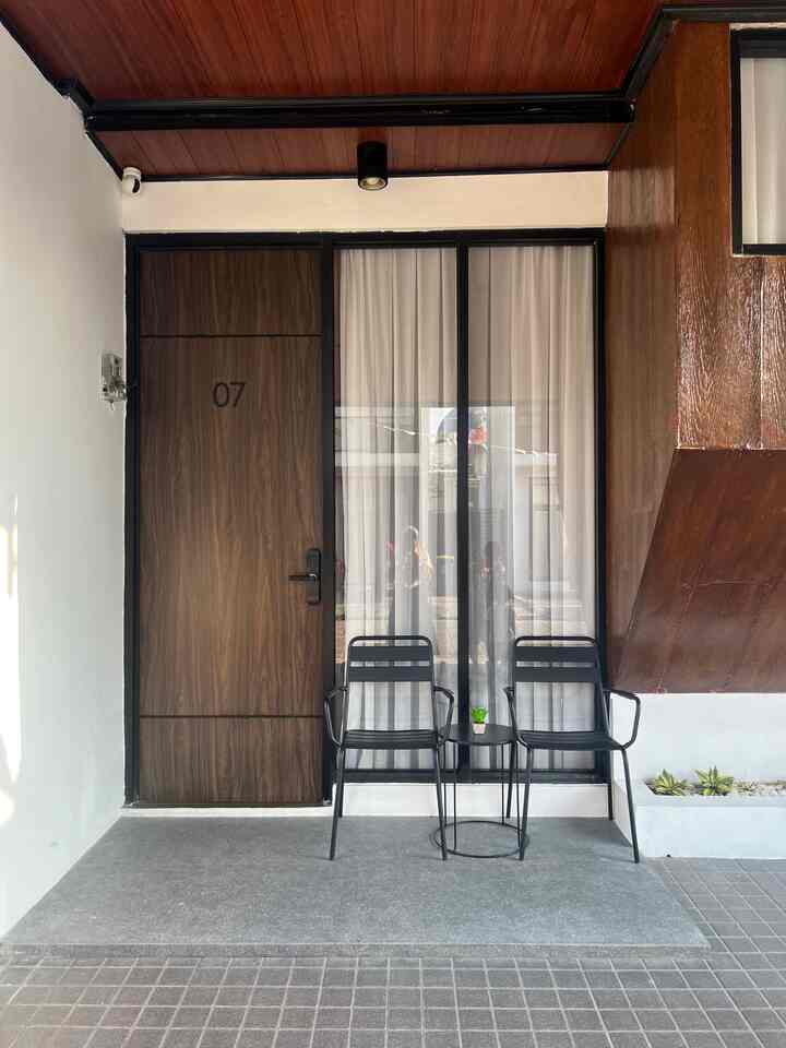 Black and brown toned entrance area featuring two side chairs and a small side table in a simple outdoor space