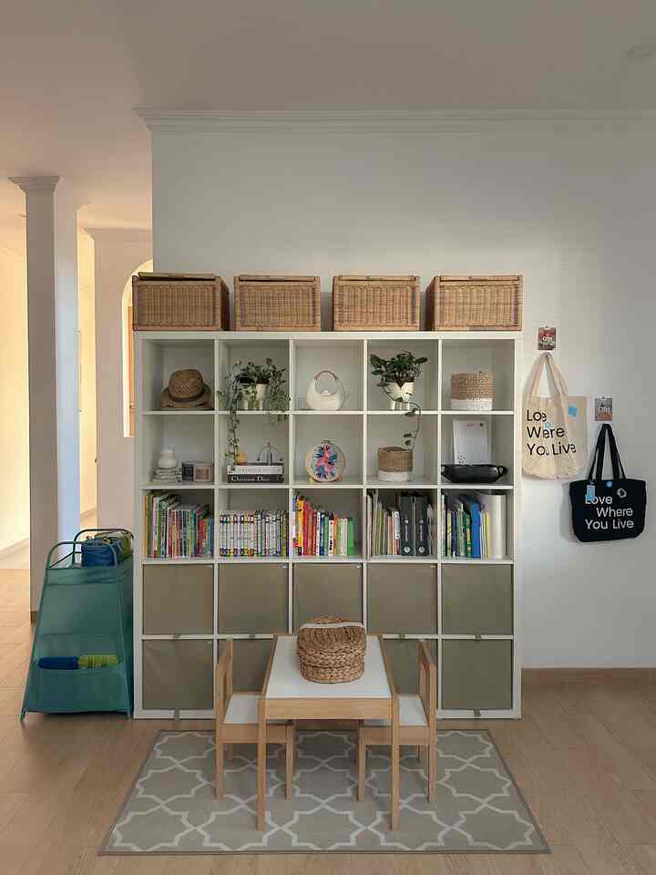 A white and natural toned kids' room featuring a small wooden table, chairs, and organized storage cabinets creating a cozy atmosphere