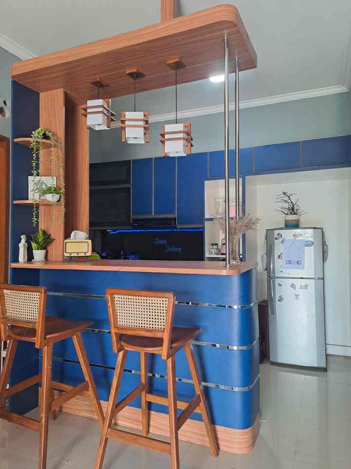 Navy and wood tone kitchen home bar featuring wooden bar stools and pendant lights, creating a cozy space