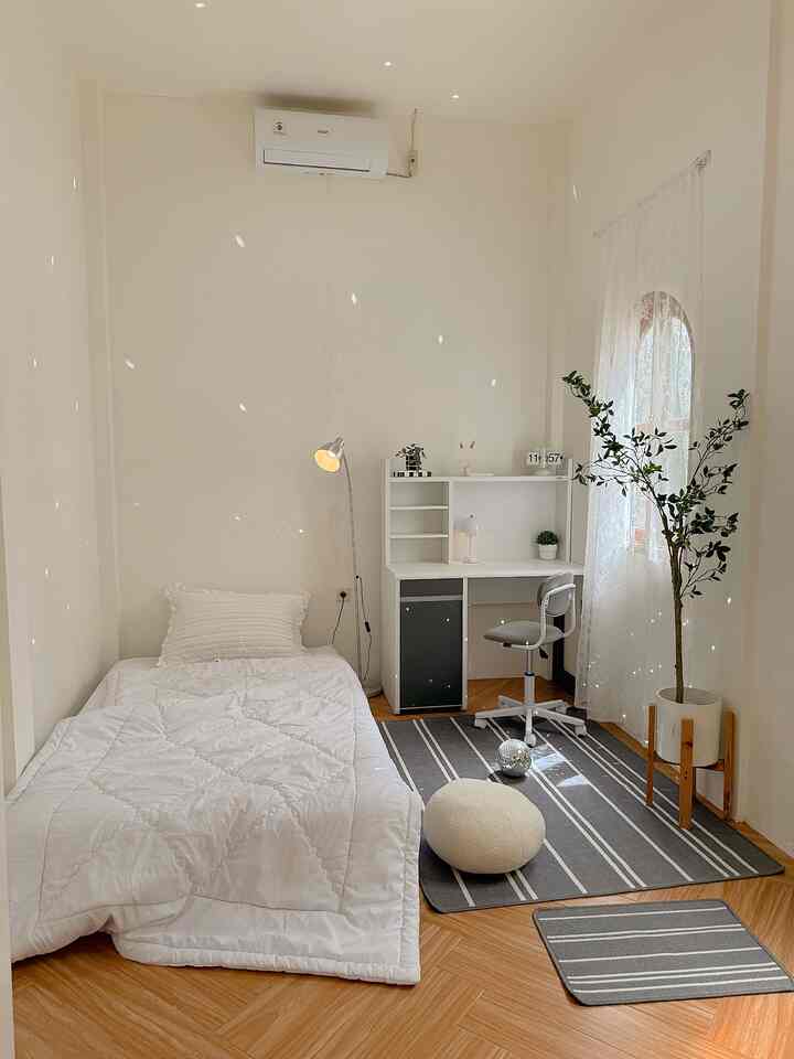 White and wood tone kids' room featuring a simple bed and desk in a clean, minimalistic space