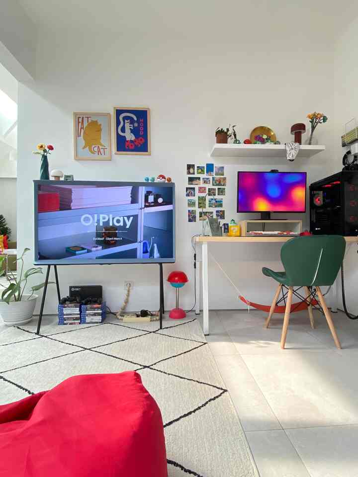 White-toned mid-century modern game room featuring a red bean bag, large TV, and a desk with computer setup for a cozy atmosphere