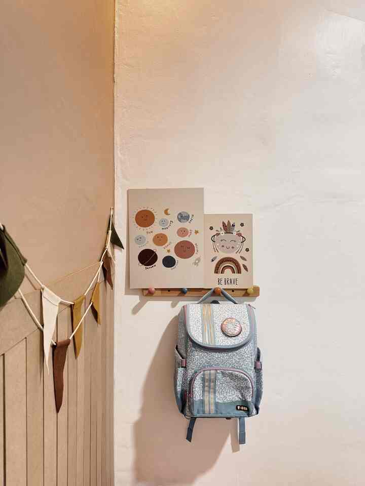 A beige-walled kids' room corner featuring a child's backpack and whimsical educational posters creating a cozy atmosphere