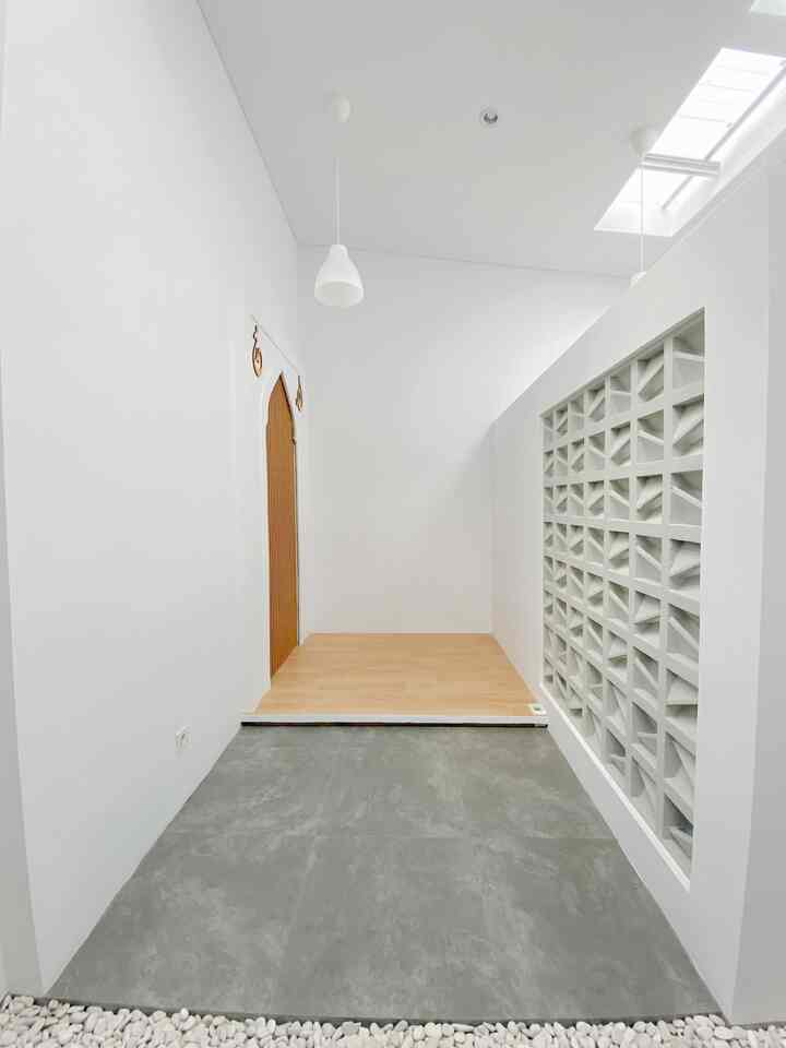 White and gray toned long narrow space featuring a prayer room door and roster wall with simple, clean interior design