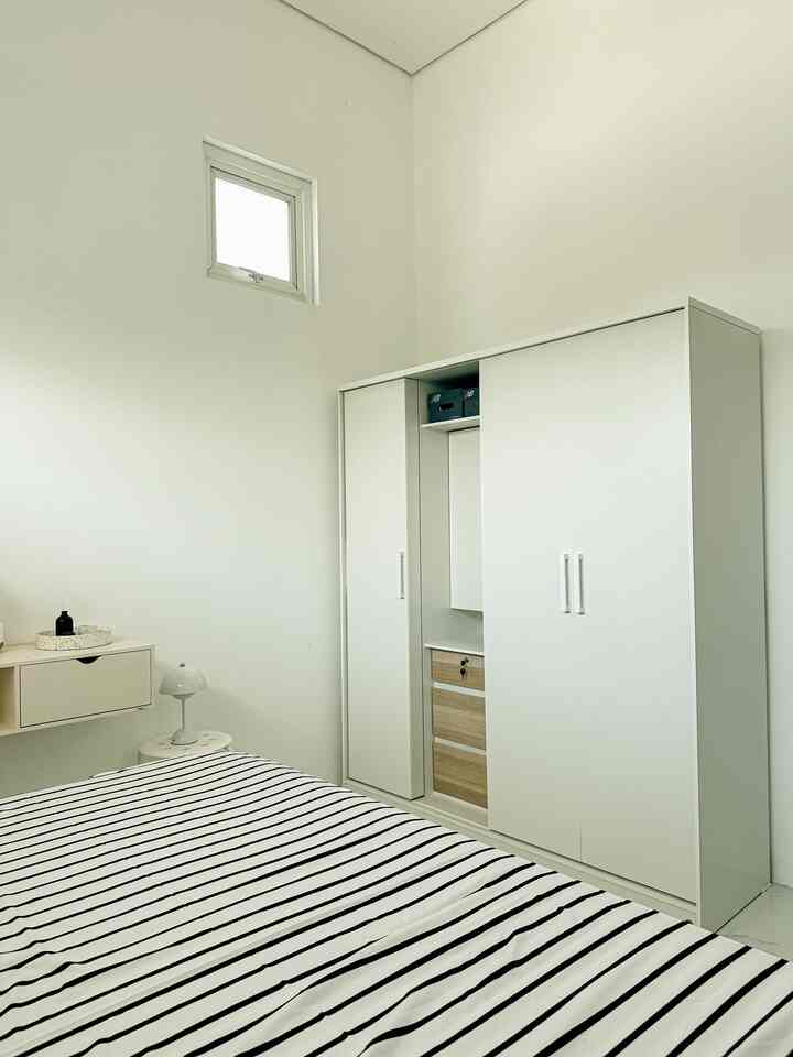 A white-toned bedroom featuring a large wardrobe and striped bedding in a modern setting