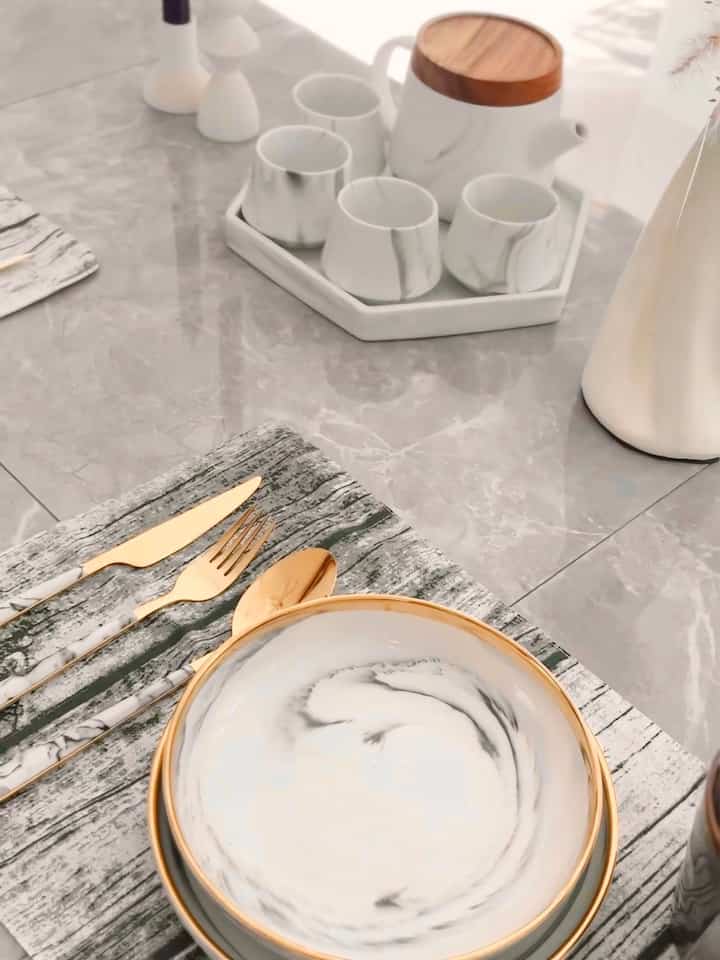 White and gold tone home cafe table featuring marble pattern dishes and cups in a stylish setting