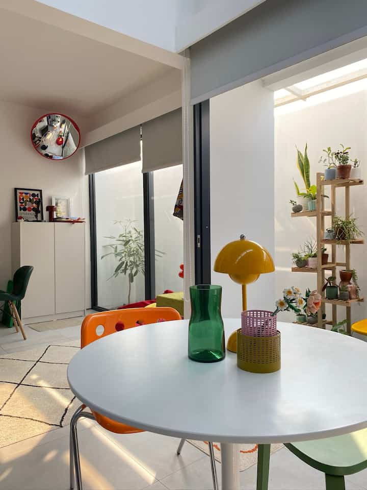 Bright dining room in white and yellow tones featuring a round dining table with colorful chairs and modern decor