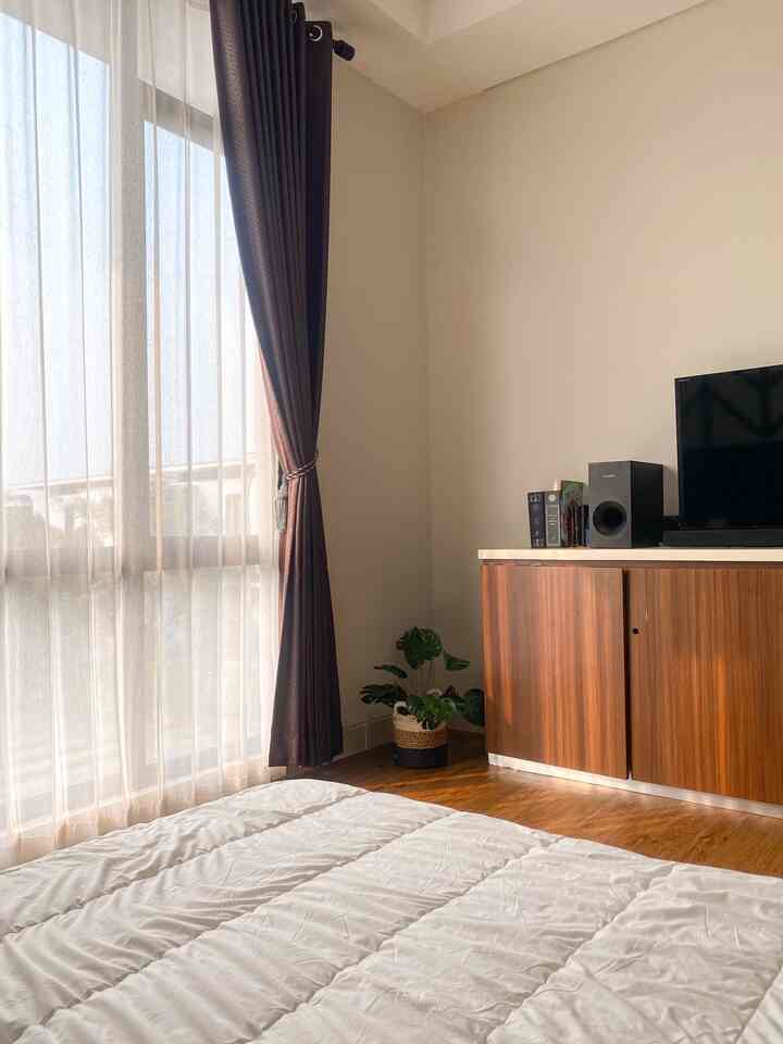 Soft white and wood-toned 6-tatami bedroom featuring tidy bedding, curtains, and a TV stand for a cozy atmosphere