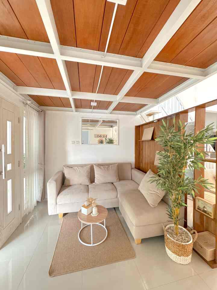 Beige-toned living room featuring a wood-toned ceiling, beige sectional sofa, white walls, and natural plant, creating a cozy atmosphere