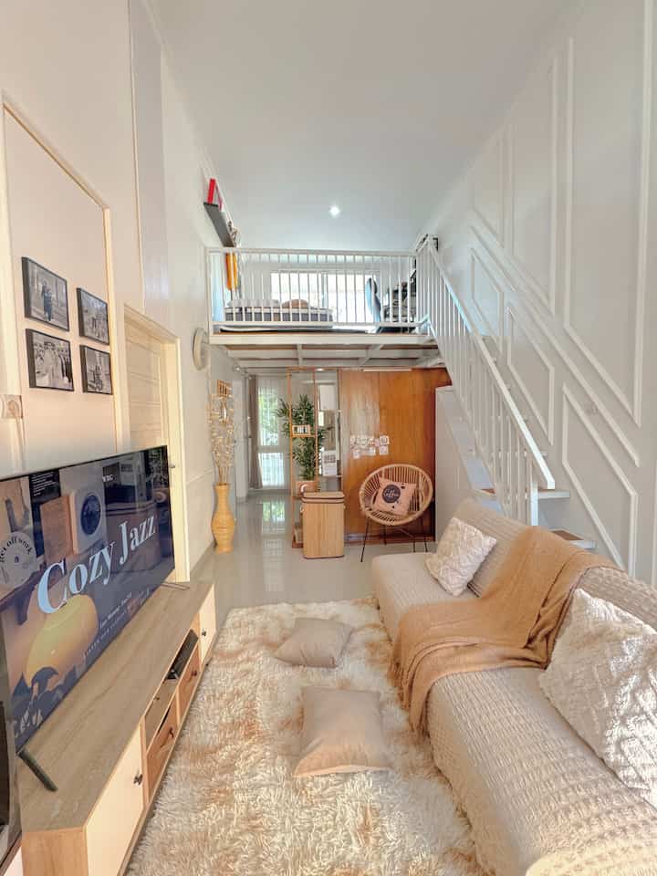 A bright and warm living room with white and beige tones featuring a cozy loft space