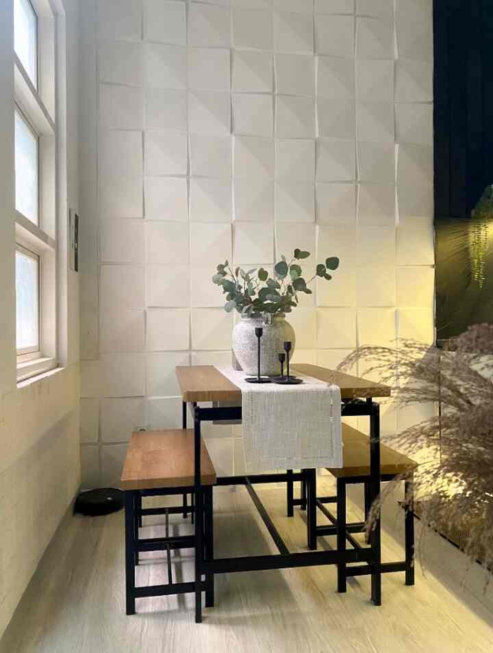 Natural wood tone dining room with white textured wall, featuring a 3-person dining table with benches and minimalist decor