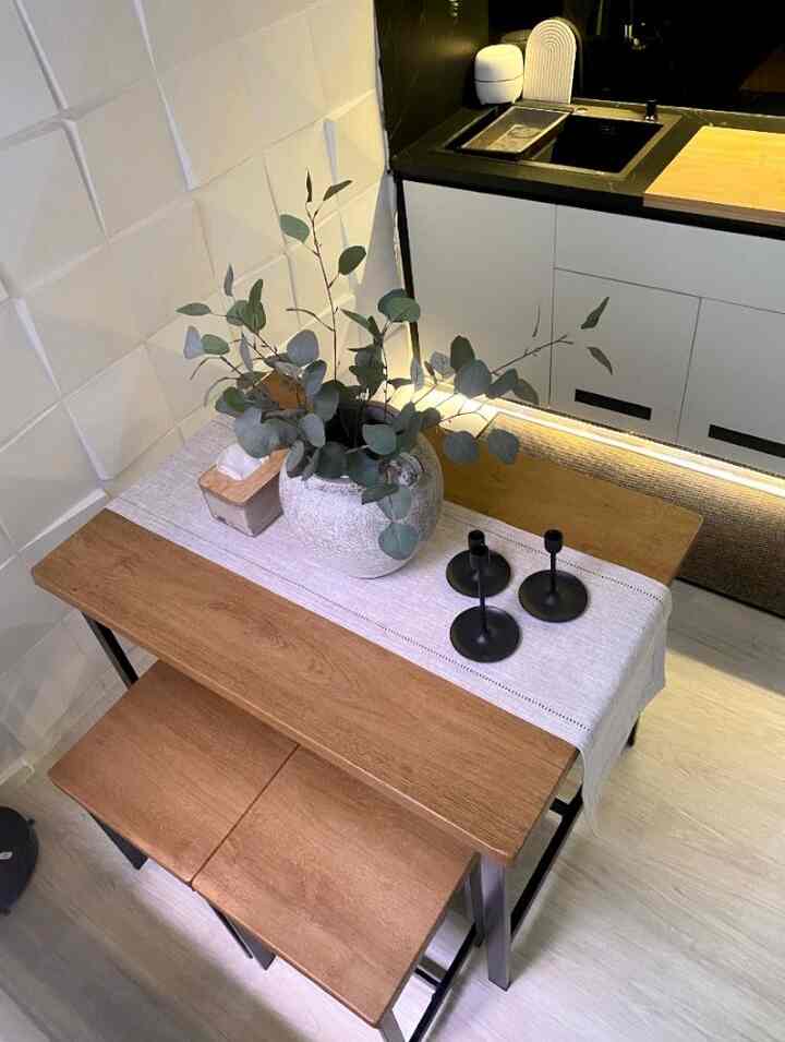 Natural wood-toned compact kitchen dining area featuring a white 3D textured wall and table runner with a cozy atmosphere