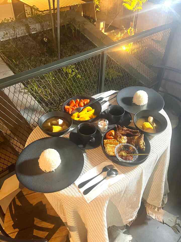 Saat merancang ruang makan yang nyaman dan ramah untuk keluarga, aku ingin memastikan setiap elemen yang dipilih menciptakan suasana hangat dan fungsional. Karena kami hanya tinggal berdua, ruang makan di rumah sering kali berpindah-pindah, mulai dari ruang tamu di depan kabinet TV, meja bar, hingga balkon—tempat favorit kami untuk sarapan atau makan malam romantis.

Balkon ini adalah contoh sempurna bagaimana kami memanfaatkan ruang luar sebagai ruang makan. Meja dan kursi di sini terbuat dari HPL board dengan rangka besi, sehingga tetap kokoh dan nyaman meskipun ukurannya kecil, hanya cukup untuk dua orang. Peralatan makan seperti piring dan gelas yang kami pilih berbahan keramik—tidak hanya stylish, tetapi juga menambah kesan elegan saat digunakan. Uniknya, taplak meja yang kami pakai adalah daur ulang dari sofa lama, kini berfungsi sebagai aksen dekoratif di meja makan kecil kami.

Untuk ruang makan yang ramah anak, memilih material yang aman dan tahan lama adalah kuncinya. Gunakan furnitur dengan sudut tumpul, material yang mudah dibersihkan, dan tekstil yang lembut namun kuat. Namun bagiku, yang terpenting adalah menciptakan suasana yang nyaman dan penuh cinta, baik itu di ruang makan formal ataupun balkon.

Tips utama? Fleksibilitas adalah segalanya. Buat ruang makan menjadi tempat di mana momen bersama terasa hangat, nyaman, dan pastinya tidak membosankan!

#MejaMakanMinimalis #InspirasiRuangMakan #DiningRoomStyling #RuangMakanRamahAnak #SuasanaHangat