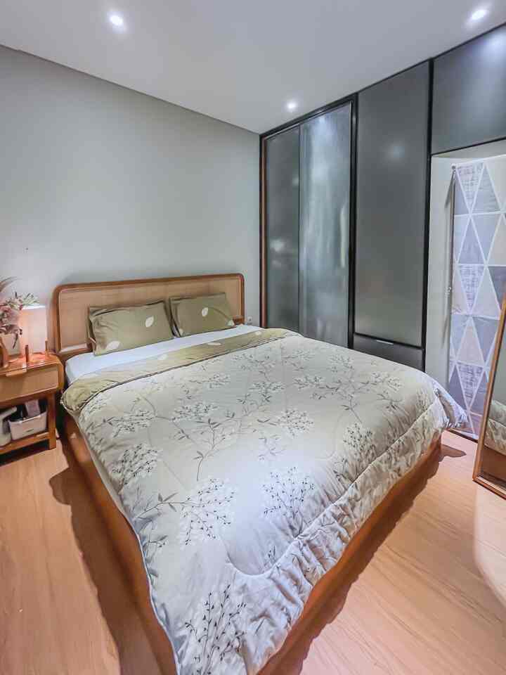 Beige and wood tone bedroom featuring a centrally placed bed with bedding, creating a cozy atmosphere