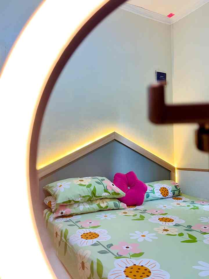 Light gray wall and white ceiling bedroom featuring floral bedding and pink cushion, creating a cozy atmosphere