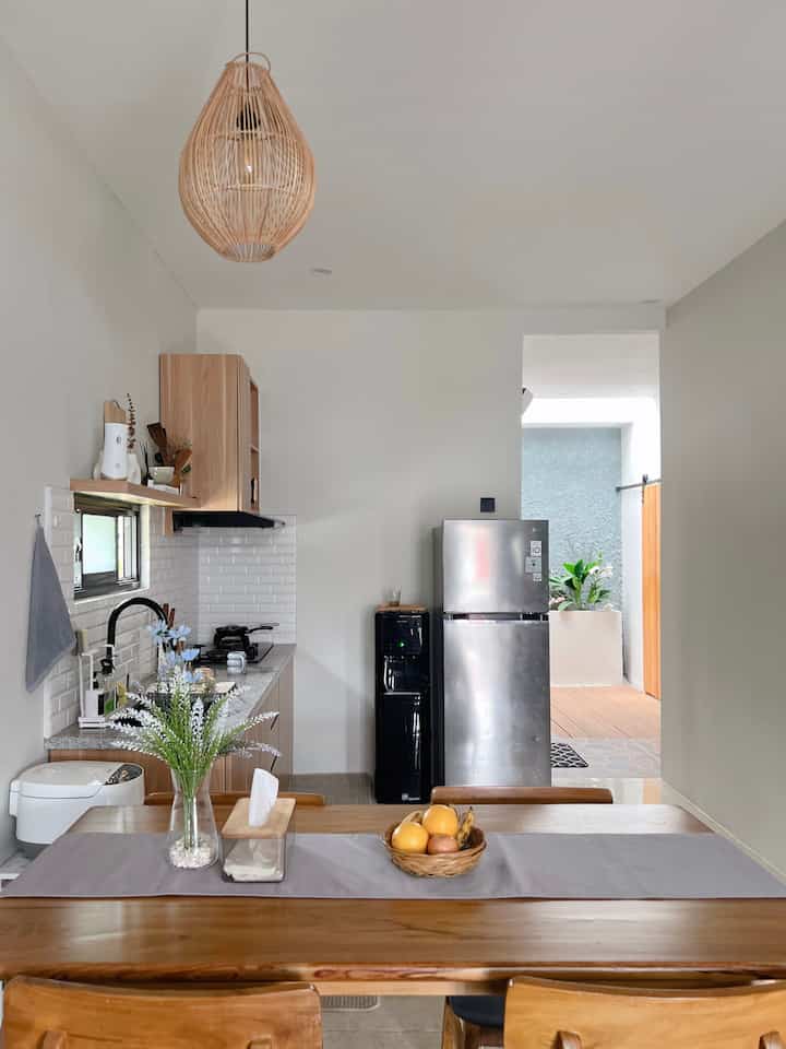 Natural color wood tone kitchen space featuring a wooden dining table with a gray table runner and chairs, creating a cozy atmosphere