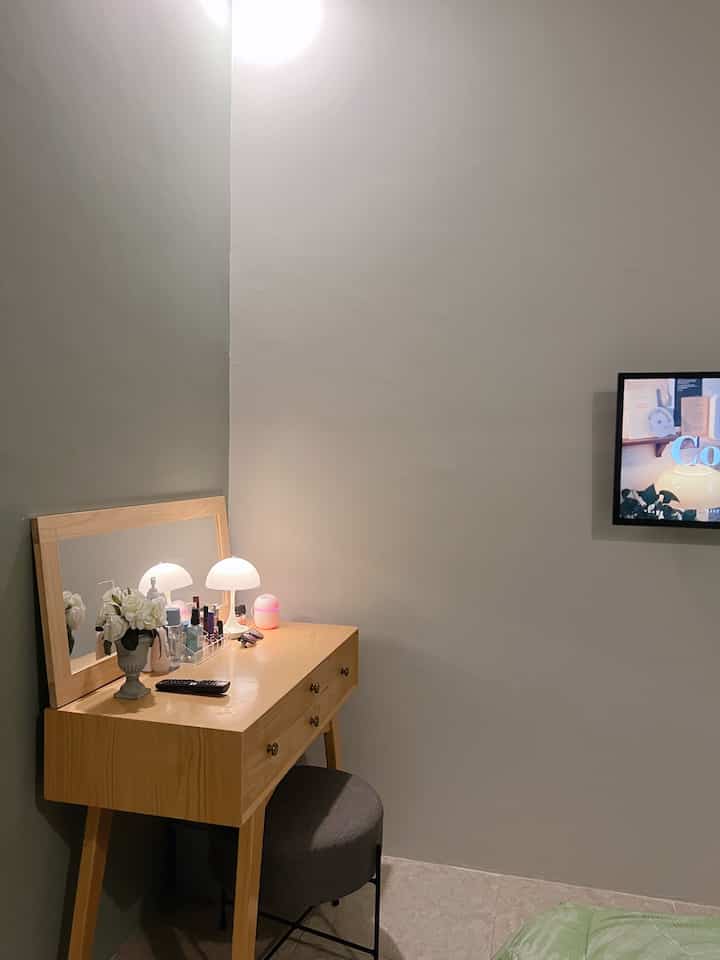Beige toned natural modern bedroom featuring a vanity with lamps and gray stool in a cozy atmosphere