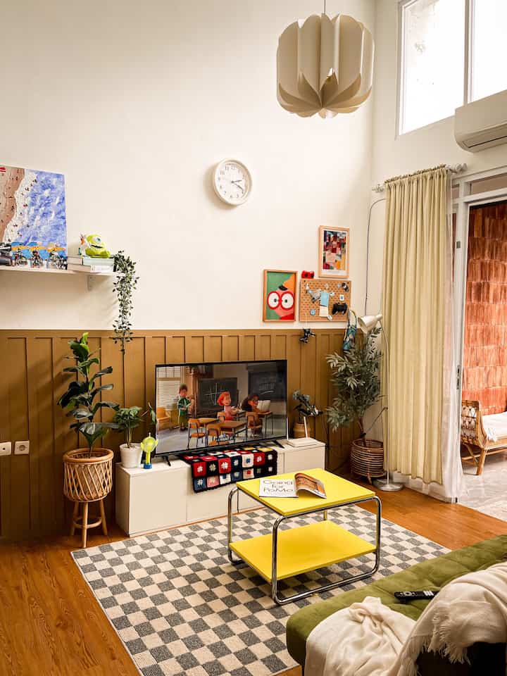 Natural color and yellow toned living room featuring sofa bed, side table, and TV stand in a cozy atmosphere