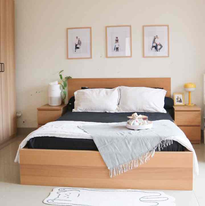 Warm-toned Japandi bedroom featuring white walls, wood tone bed frame, matching nightstands, and subtle decor accents