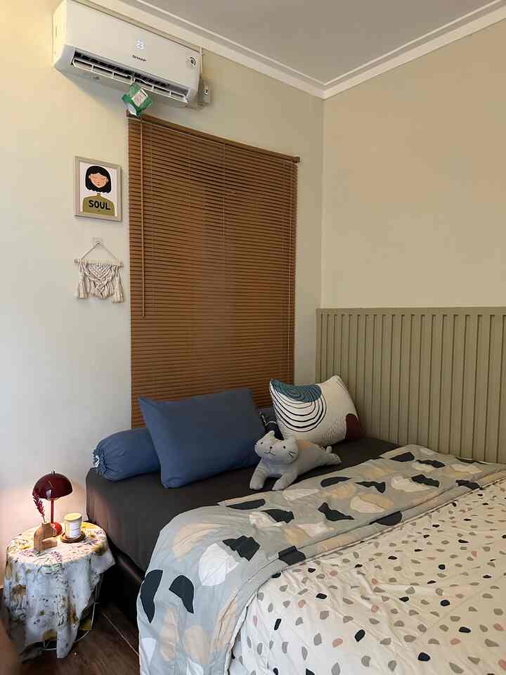 Natural beige and brown toned bedroom featuring olive green headboard, brown blinds, simple bed and cushions creating a cozy atmosphere