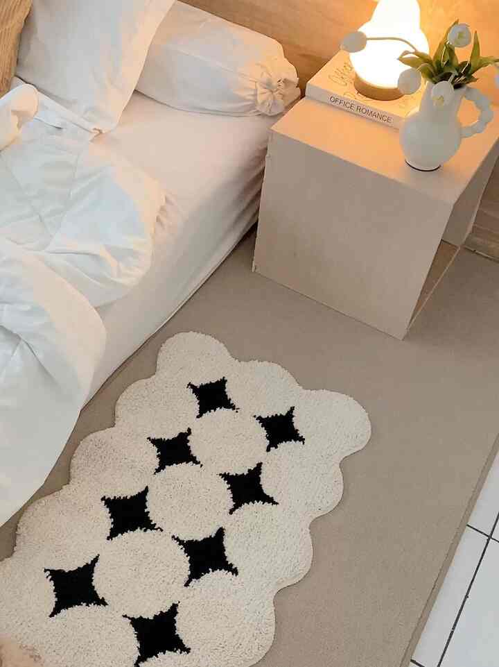 White and beige toned bedroom featuring a white bed and a small nightstand topped with lamp and vase, cozy atmosphere