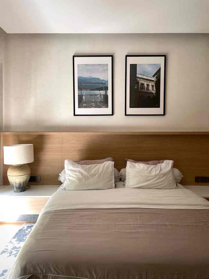 A modern minimal bedroom in beige and white tones featuring a built-in bed frame, nightstands, and framed pictures on the wall