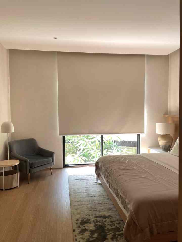 Natural toned bedroom space featuring beige roller blinds and wood furniture with a calm, cozy atmosphere