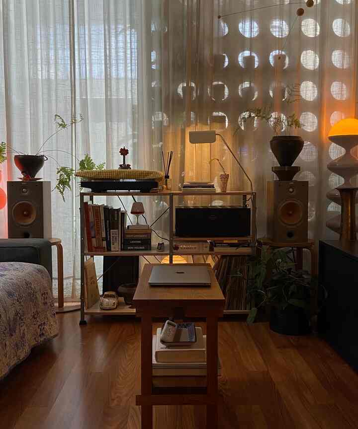 Natural tone living room featuring wood tone flooring, beige curtains, and bookshelf creating a warm atmosphere