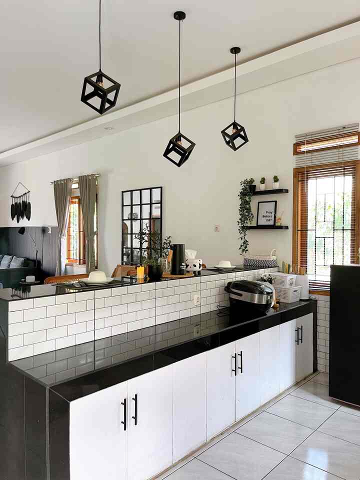 Monochrome kitchen space featuring sturdy granite bar counter and geometric cube pendant lights in a minimal style