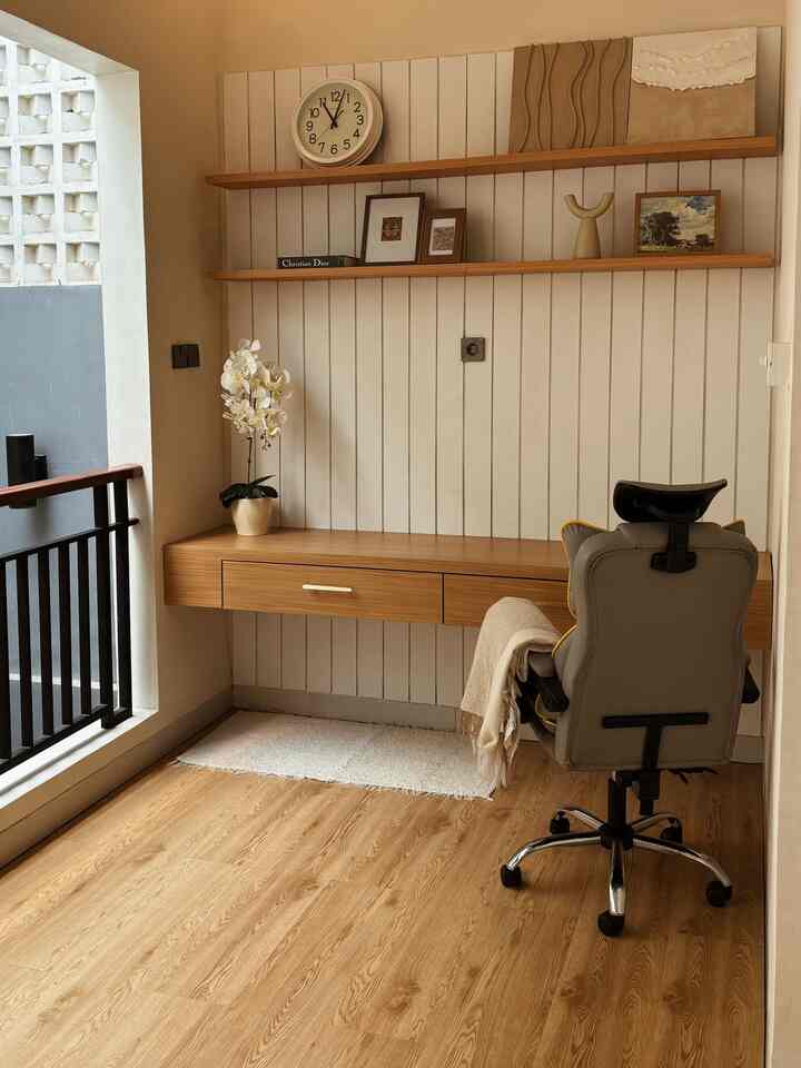 Natural color wood-tone small home office space beside a balcony with desk and office chair arranged for a cozy atmosphere