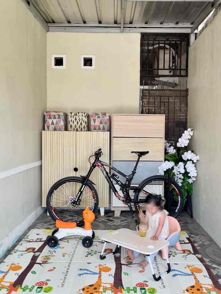 Beige-toned small room featuring baby play mat, toys, and bicycle indicating a living space with a baby