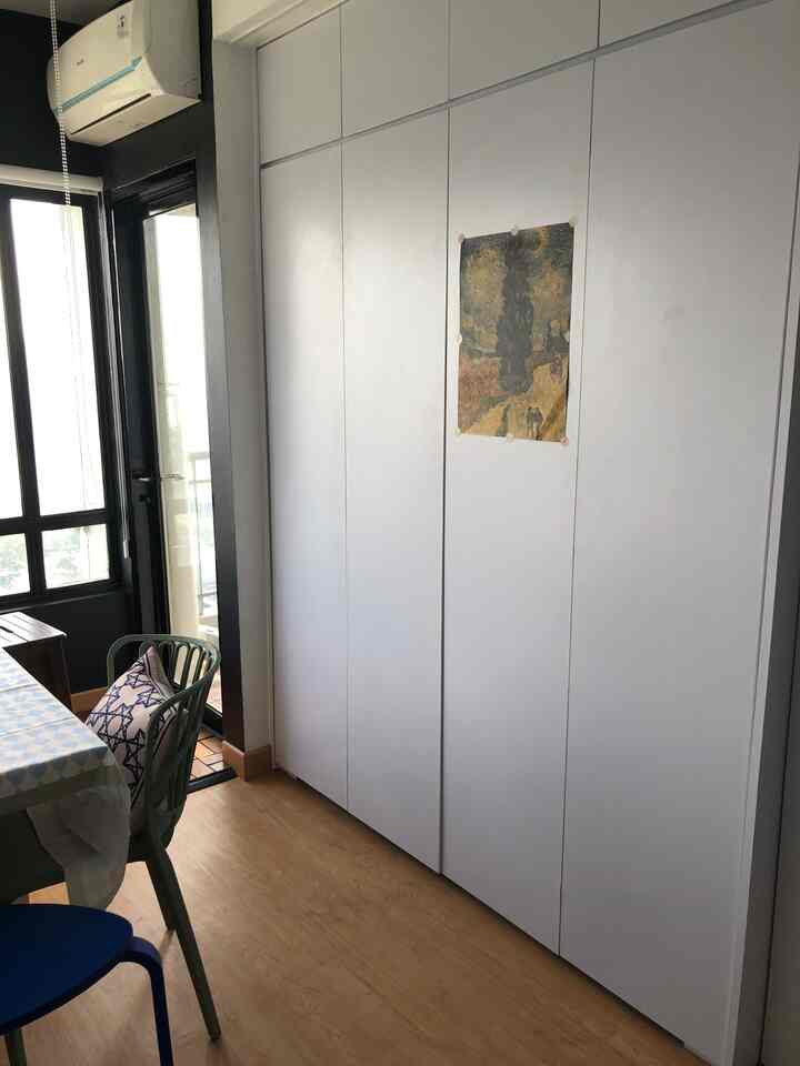 Dining room with white wall closet and wood tone flooring, featuring a dining table and chairs in a neat setting