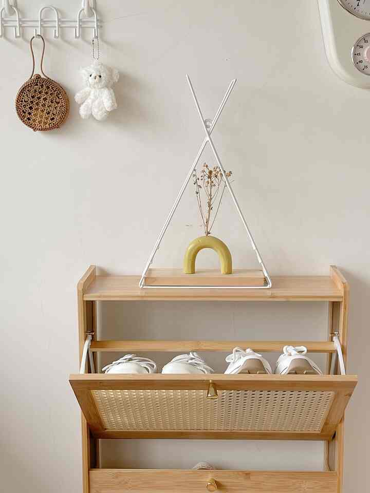 Modern entrance space featuring a natural wood tone shoe cabinet against a beige wall