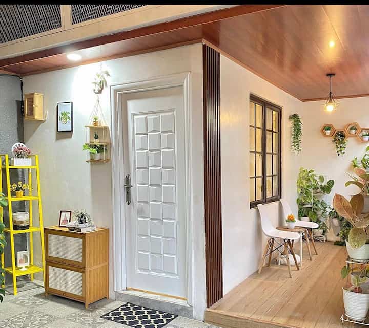 Natural small terrace with white walls and wood tone ceiling, featuring plants and minimalist furniture creating cozy cafe style atmosphere