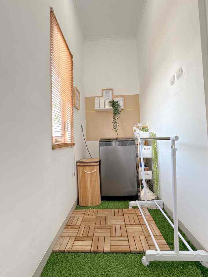 Natural brown and white toned narrow laundry space featuring washing machine, storage basket, and drying rack with practical layout