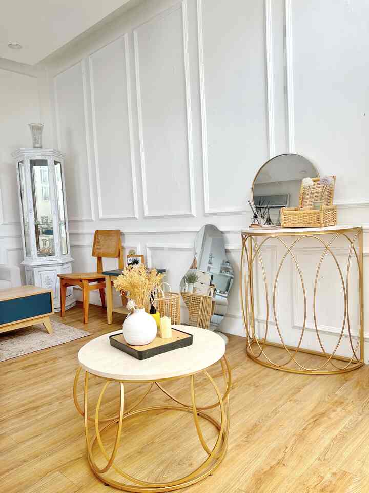 Natural modern living room with white walls and gold frame furniture featuring a round coffee table and mirrors