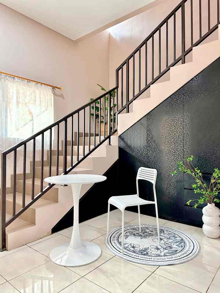 A white and black dining room featuring a simple round dining table and chair arranged neatly under the stairs