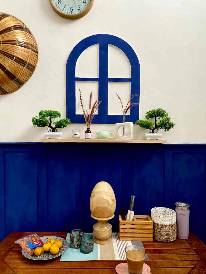 Cozy dining space with navy walls and natural wood table, decorated with vases and tableware creating a relaxing home cafe vibe