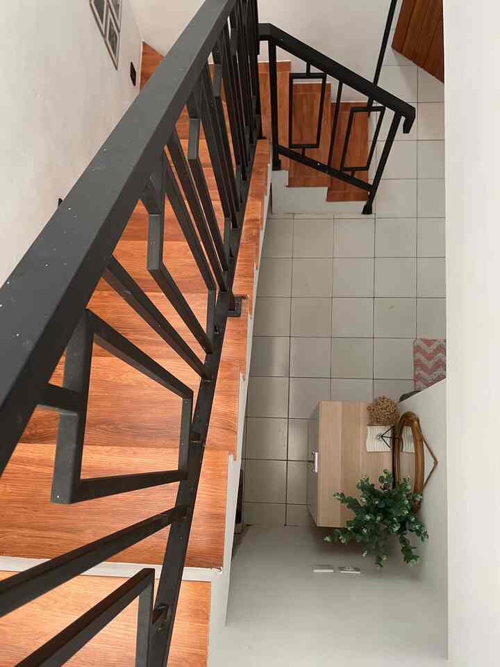 White and brown toned under-stair bathroom gap storage featuring a rattan mirror and artificial plant with a cozy natural atmosphere