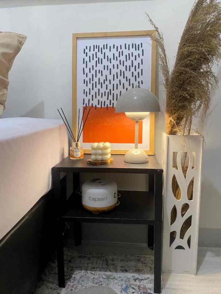 White and black toned bedroom corner with nightstand featuring table lamp and diffuser, creating a cozy natural ambiance