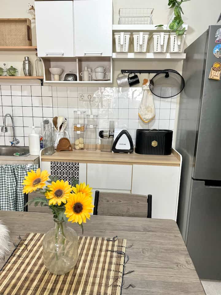 White and wood tone kitchen featuring dining table with runner and neatly arranged kitchen accessories